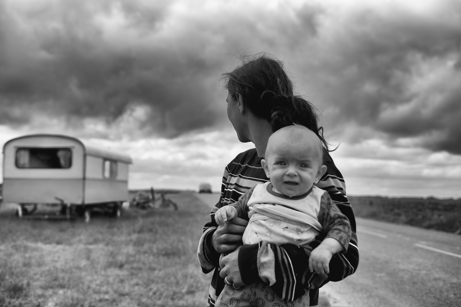 woman carrying baby looking at camper trailer